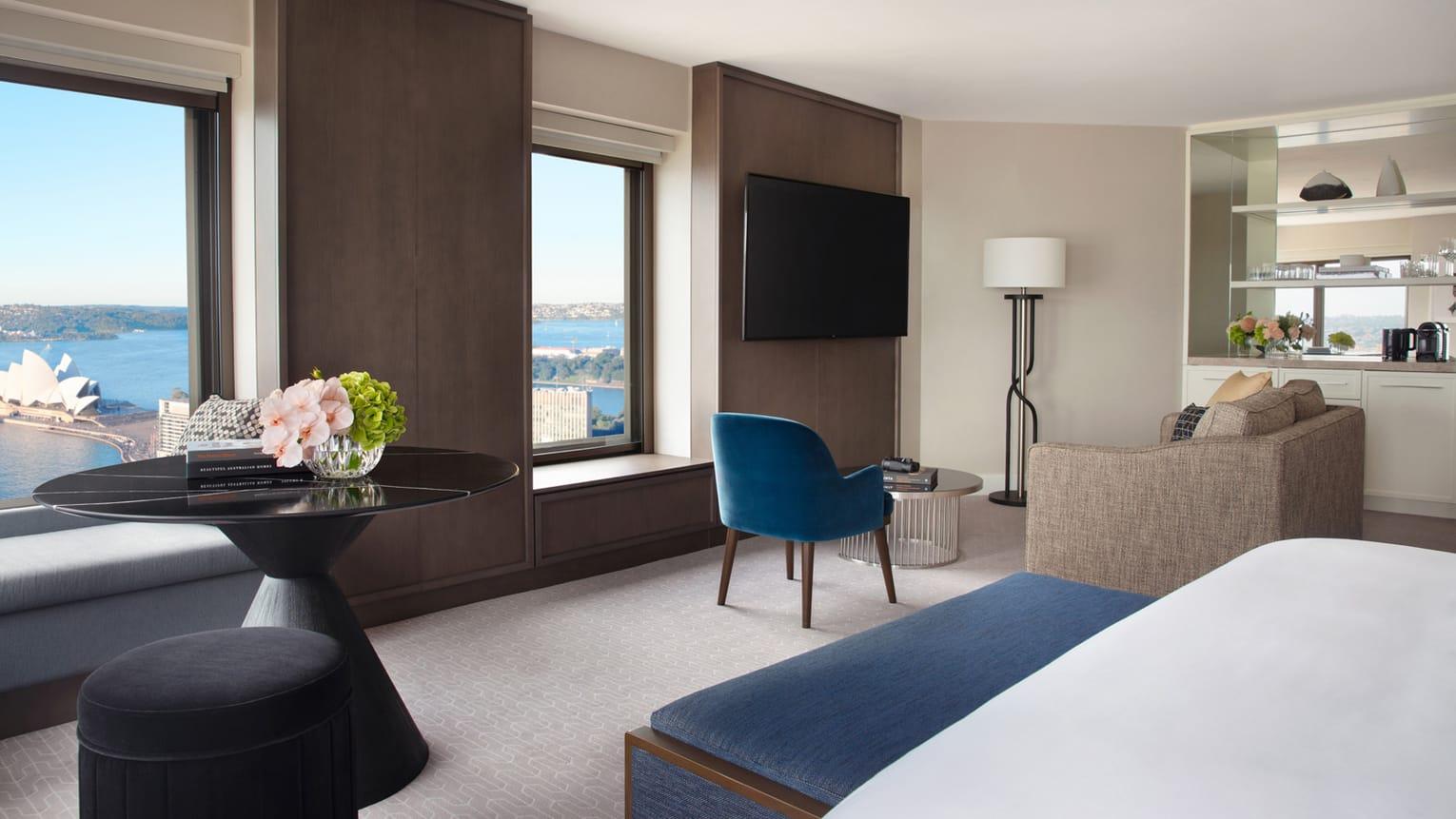 Four Seasons Hotel Sydney Exterior photo The photo showcases a modern hotel room with a sleek and contemporary design. It features a large window that offers a view of the outside. The room includes:

- A comfortable seating area with a blue chair and a light-colored sofa.
- A round black t